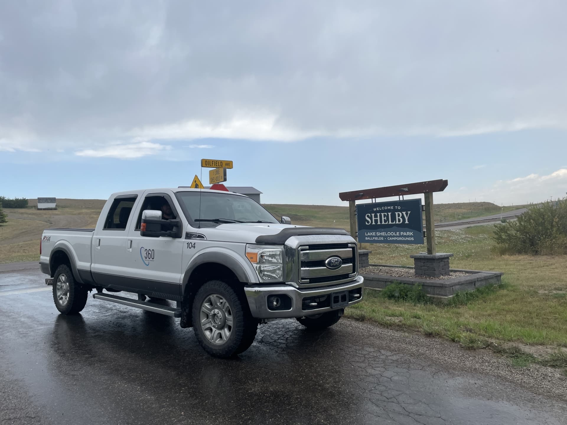 A 360 company truck entering Montana for 360's first project in the USA. The photo shows a white truck with a 360 logo on the door parked in front of the "welcome to Shelby" sign.