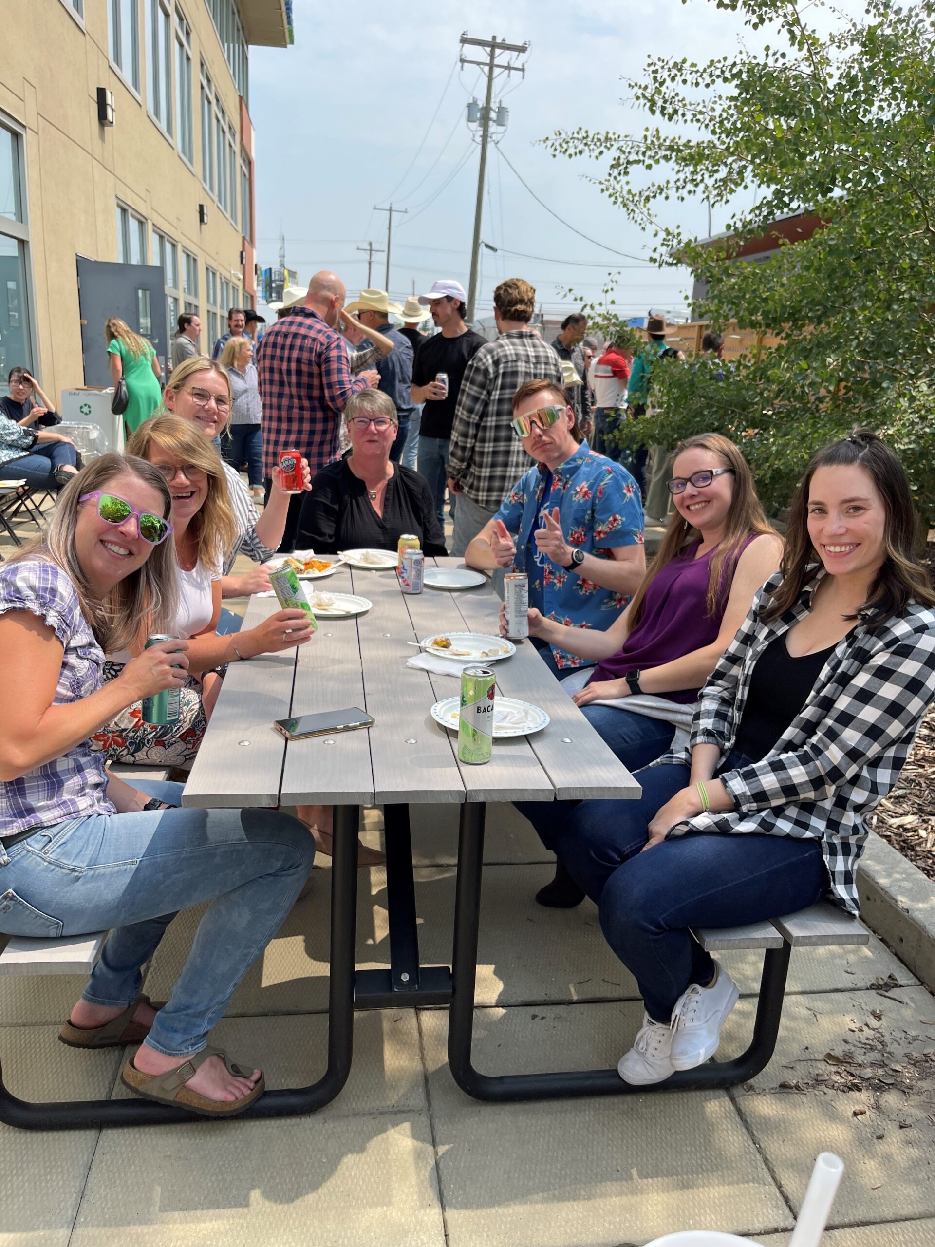 360 employees sitting around a picnic table at a company event. The event was a Stampede barbecue so employees are dressed in western attire. The photo shows 7 people.